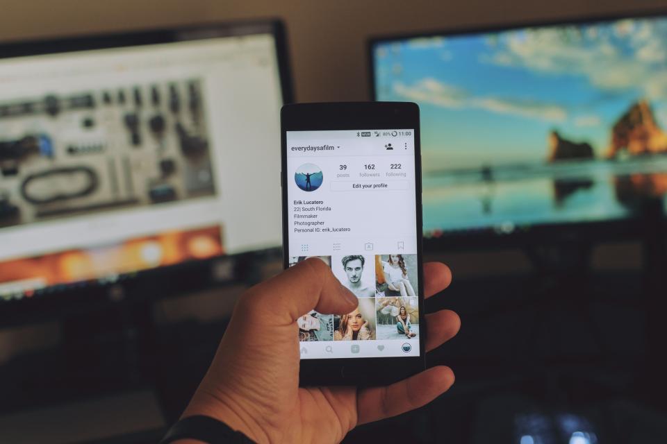 Two people at a desk, one holding a phone with an app screen open